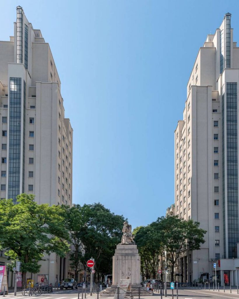 Les tours des Gratte-Ciel de Villeurbanne encadrant une avenue arborée, ciel bleu