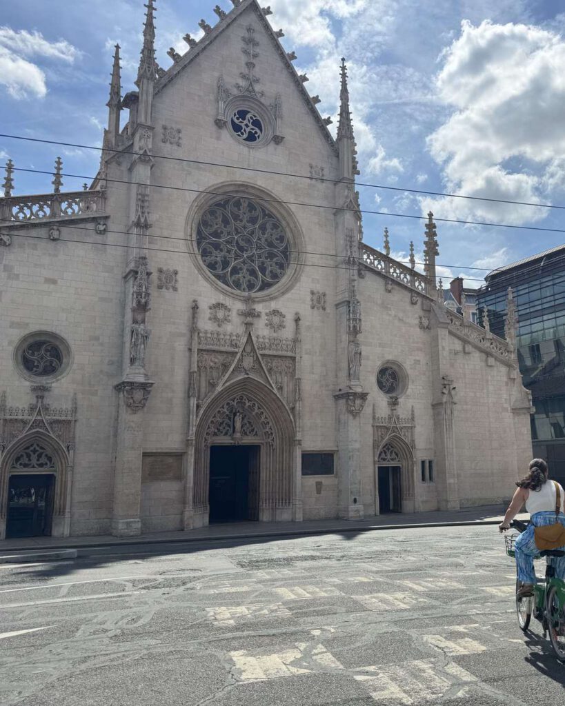 Façade gothique de l'église Saint-Bonaventure à Lyon, grande rosace, cycliste traversant la place ensoleillée